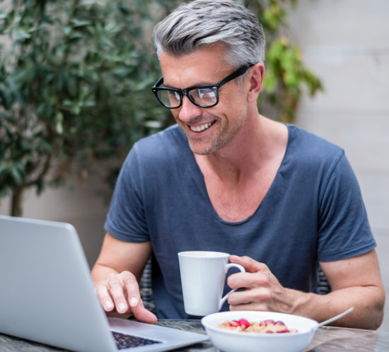 A man checking his laptop which eating breakfast - Boyd Insurance