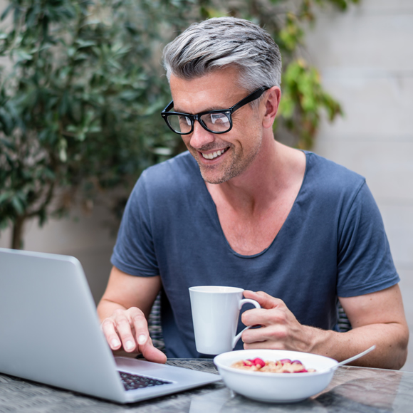 A man checking his laptop which eating breakfast - Boyd Insurance