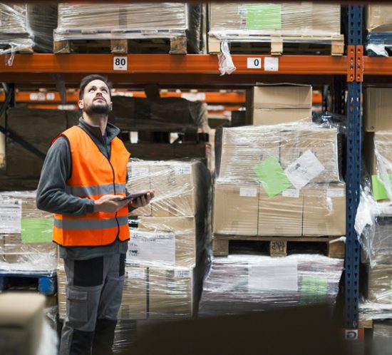 A man in a high-visibility jacket checking stock in a warehouse - Boyd Insurance