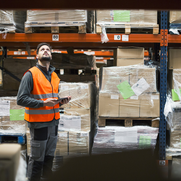 A man in a high-visibility jacket checking stock in a warehouse - Boyd Insurance